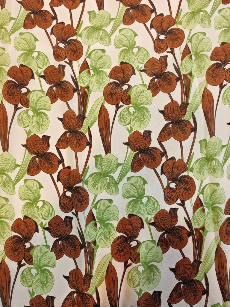 Țesătură din mătase naturală 100% tip Crepe de Chine, cu imprimeu floral de orhidee verzi și maro pe fond alb, material fin pentru rochii, bluze și fuste, lățime 140 cm, import Italia