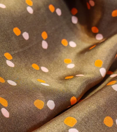 Mătase naturală Twill maro cu buline ivoir și portocaliu – textură fluidă, import Grecia Textură de mătase naturală 100% tip Twill, imprimeu cu buline ivoir și portocaliu pe fond maro, material fin pentru rochii și bluze, import Grecia