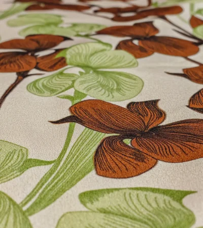 Detaliu mătase Crepe de Chine cu imprimeu floral, orhidee verde și maro Detaliu de țesătură din mătase naturală Crepe de Chine, cu model repetitiv de orhidee în nuanțe de verde și maro, textură ușor ondulată și cădere fluidă