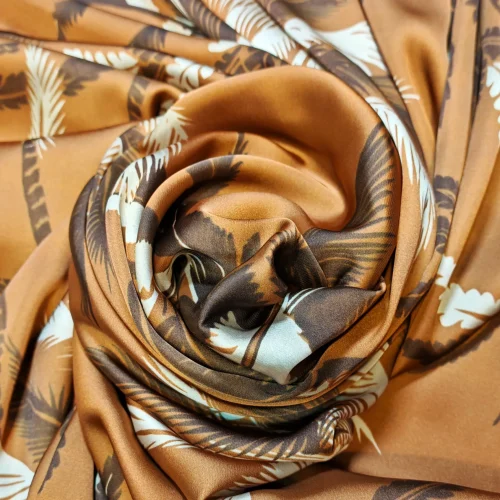 Detaliu țesătură tip saten cu model repetitiv de palmieri ivoire pe fundal muștar, material satinant ideal pentru articole vestimentare elegante și de vară